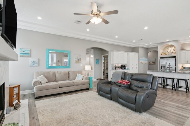 living room with crown molding, ceiling fan, and light hardwood / wood-style floors