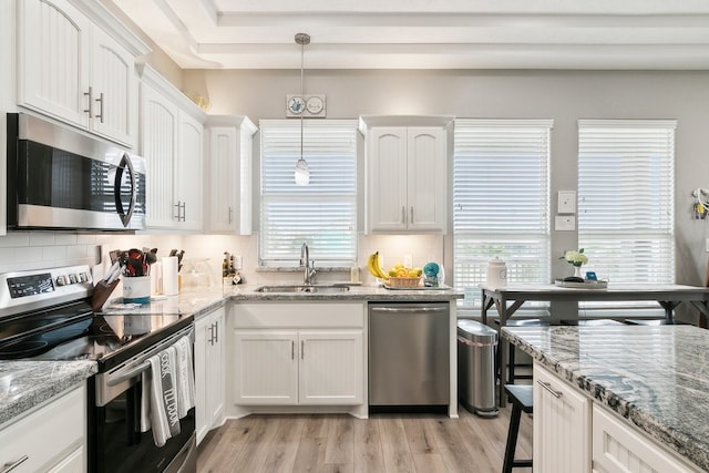 kitchen with pendant lighting, appliances with stainless steel finishes, sink, and white cabinets