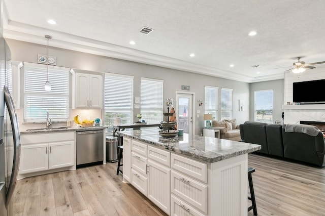 kitchen featuring sink, white cabinetry, a center island, appliances with stainless steel finishes, and pendant lighting