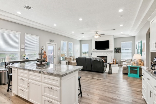 kitchen featuring light stone countertops, a kitchen island, a breakfast bar area, and white cabinets