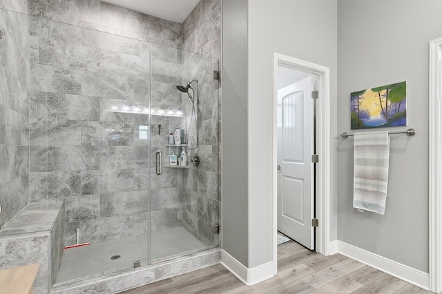 bathroom with a shower with door and hardwood / wood-style floors