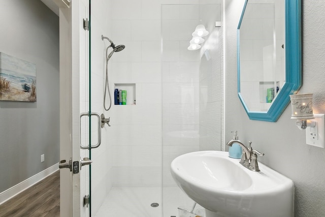 bathroom with hardwood / wood-style flooring, a shower with shower door, and sink