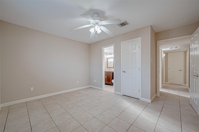 unfurnished bedroom with light tile patterned flooring, connected bathroom, and ceiling fan