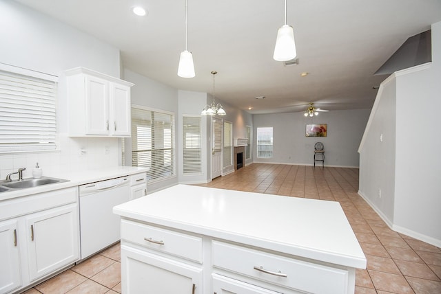 kitchen with white dishwasher, sink, pendant lighting, and white cabinetry