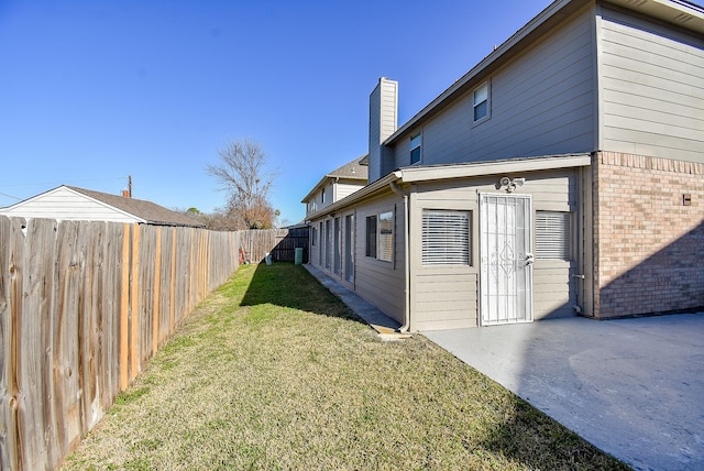 view of side of home featuring a patio and a lawn