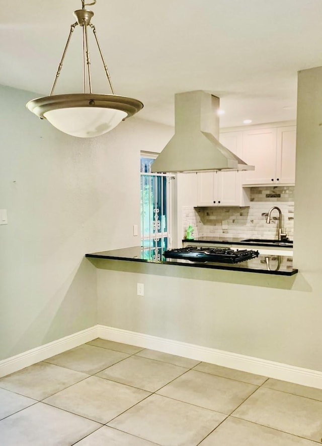 kitchen with pendant lighting, sink, island range hood, white cabinets, and stainless steel gas stovetop