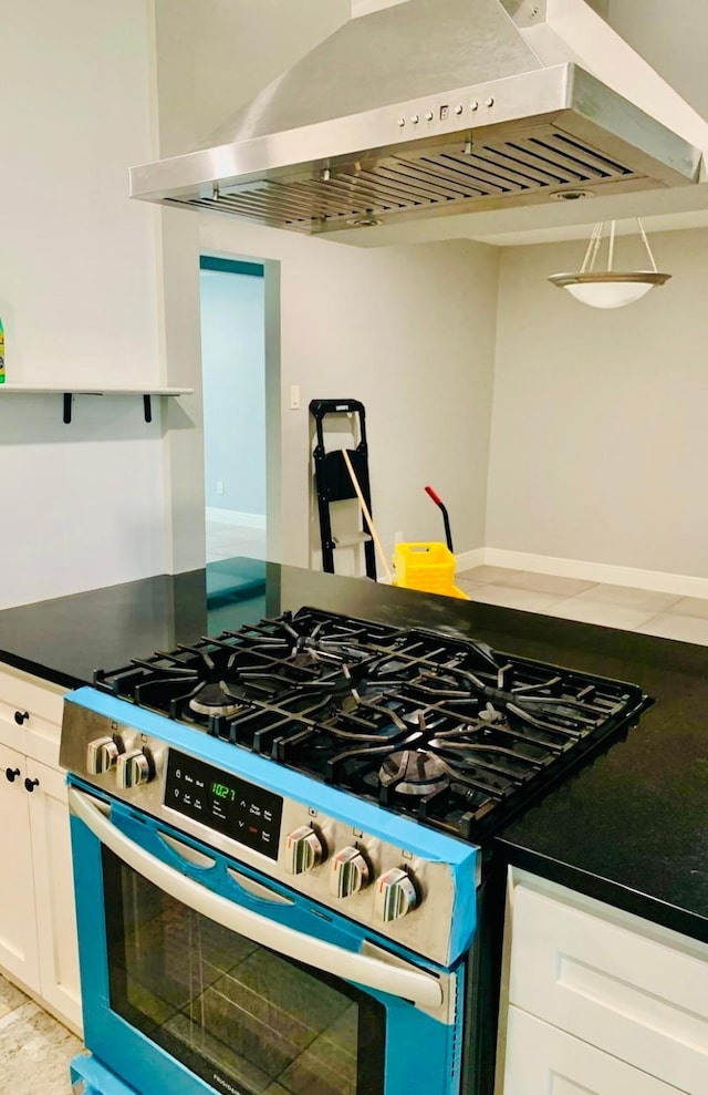 kitchen with stainless steel gas stove, extractor fan, and white cabinets