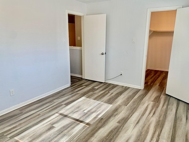 unfurnished bedroom featuring a closet, a spacious closet, and light hardwood / wood-style flooring