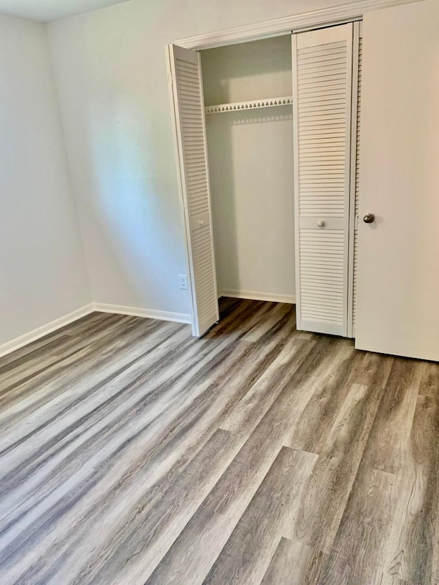 unfurnished bedroom featuring wood-type flooring and a closet