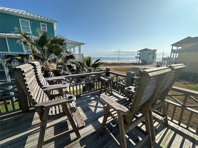 wooden terrace featuring a beach view and a water view