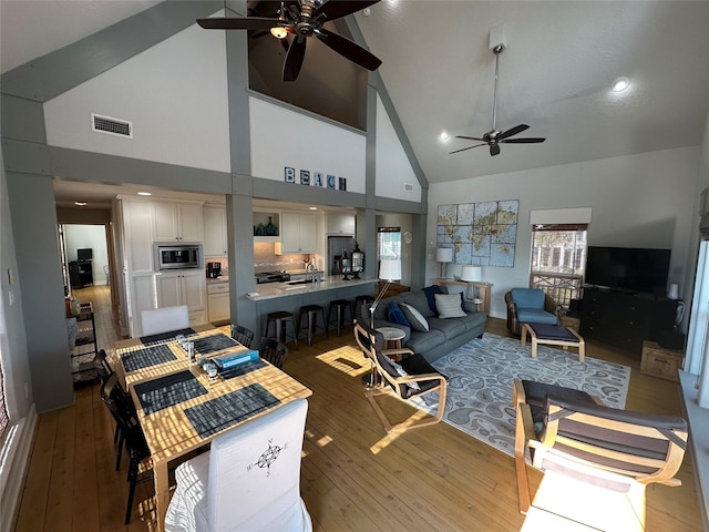 living room with sink, high vaulted ceiling, light hardwood / wood-style floors, and ceiling fan