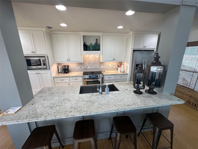 kitchen featuring backsplash, stainless steel appliances, a breakfast bar area, and white cabinets