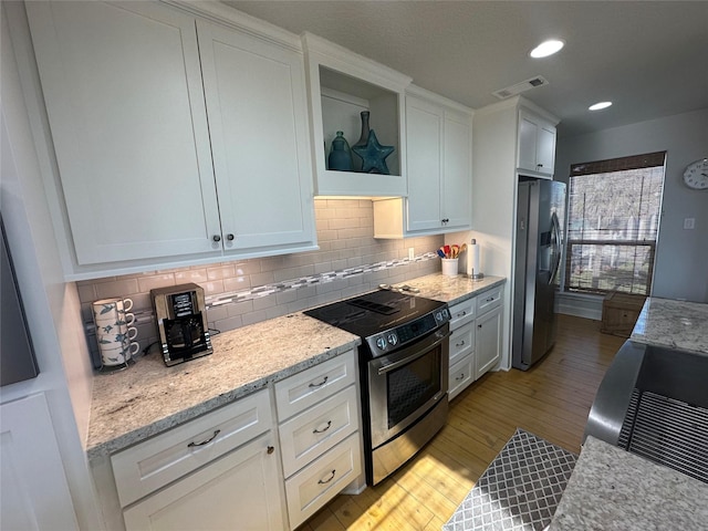 kitchen featuring light stone counters, light hardwood / wood-style flooring, white cabinets, and appliances with stainless steel finishes