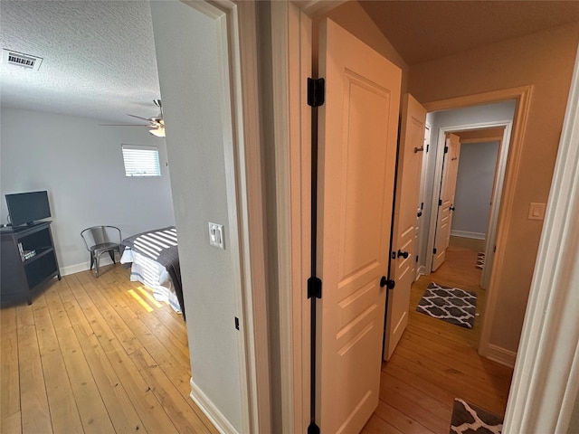 hall with light hardwood / wood-style floors and a textured ceiling