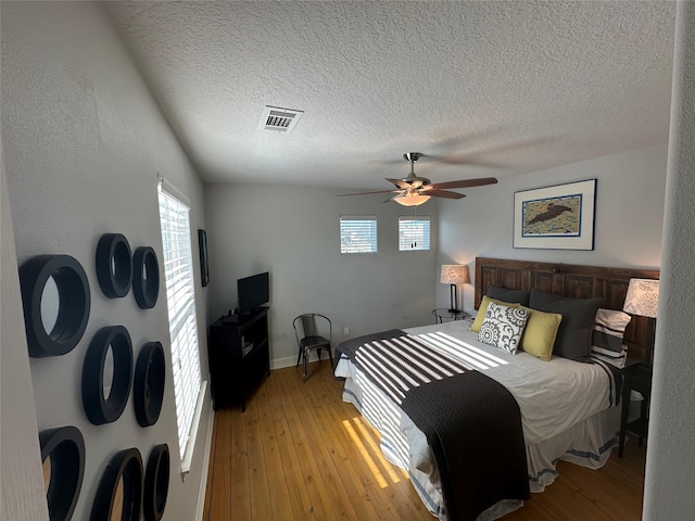 bedroom featuring multiple windows, light hardwood / wood-style floors, and ceiling fan