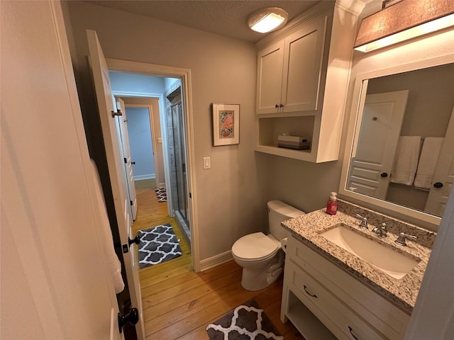 bathroom with hardwood / wood-style floors, vanity, a textured ceiling, toilet, and walk in shower