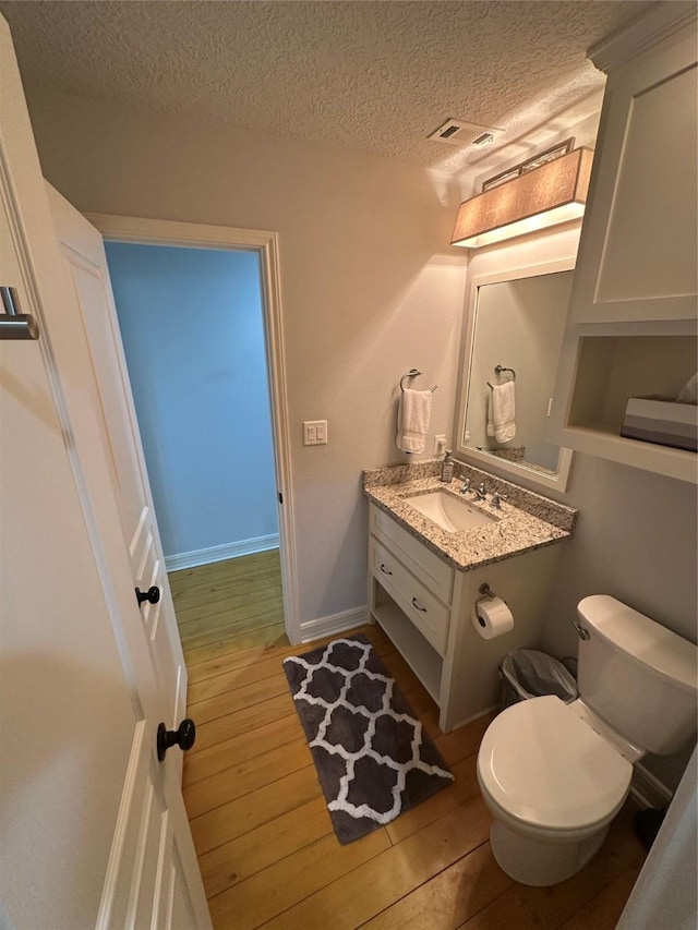 bathroom with vanity, hardwood / wood-style flooring, toilet, and a textured ceiling