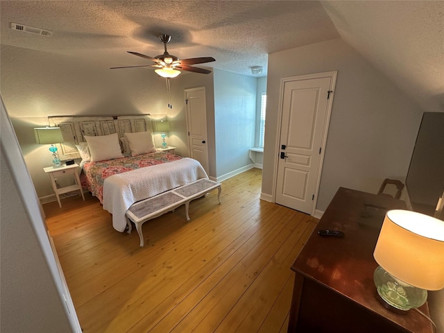 bedroom with hardwood / wood-style flooring, ceiling fan, lofted ceiling, and a textured ceiling