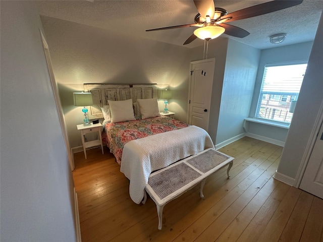 bedroom with ceiling fan, a textured ceiling, and light hardwood / wood-style flooring