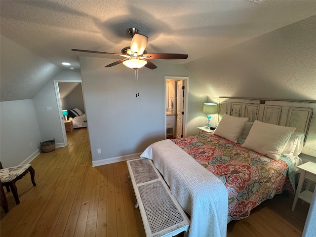 bedroom with lofted ceiling, connected bathroom, light hardwood / wood-style flooring, a textured ceiling, and ceiling fan