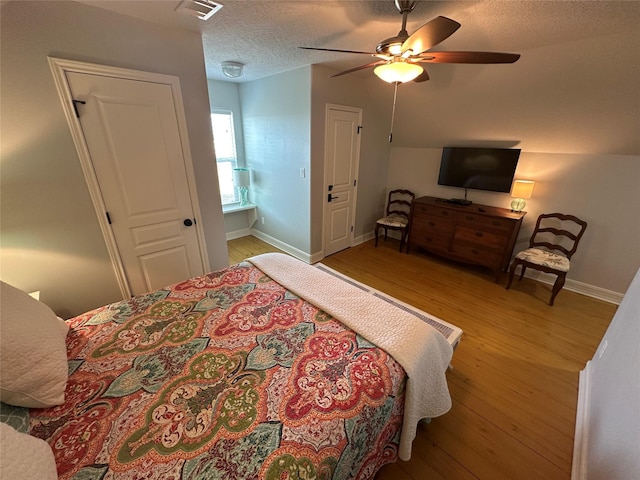 bedroom featuring ceiling fan, light hardwood / wood-style flooring, and a textured ceiling