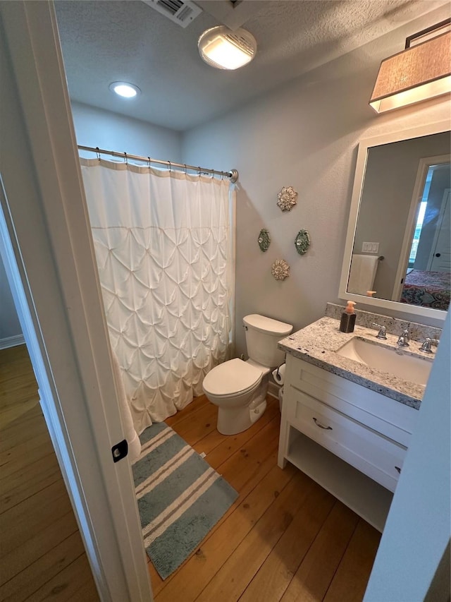 bathroom with vanity, toilet, hardwood / wood-style floors, and a textured ceiling