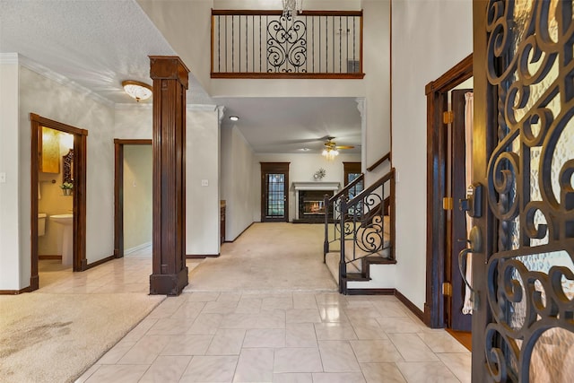 foyer featuring ceiling fan, decorative columns, light carpet, and a towering ceiling