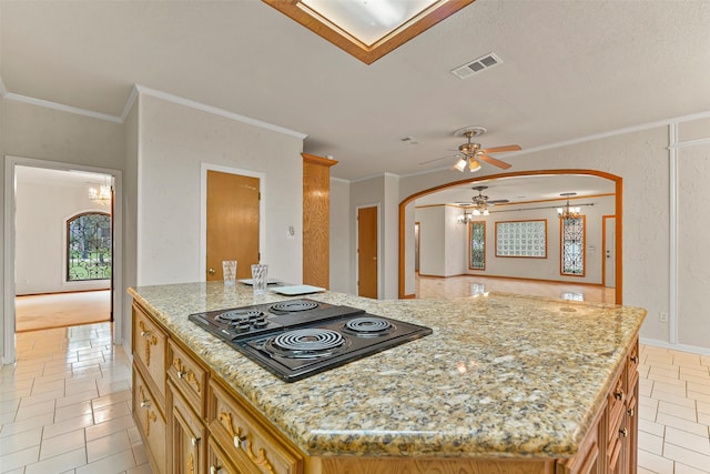 kitchen with ornamental molding, black electric stovetop, a center island, and light stone countertops