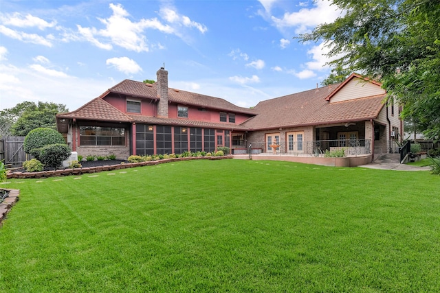 back of property featuring a lawn, a sunroom, and a patio