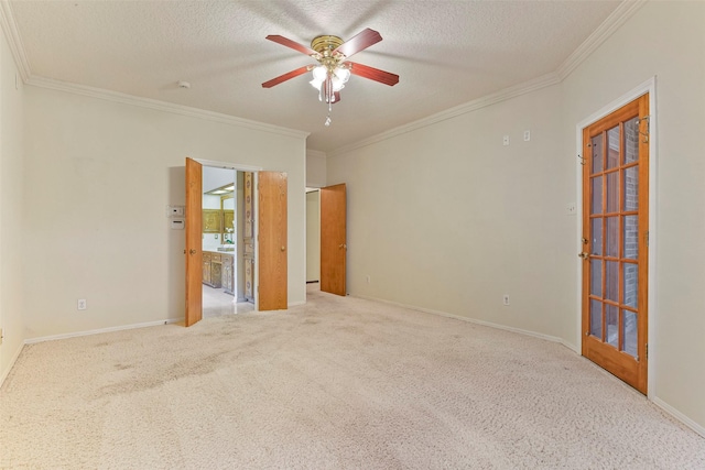 carpeted empty room featuring ceiling fan, crown molding, and a textured ceiling