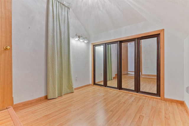 unfurnished room with wood-type flooring and vaulted ceiling