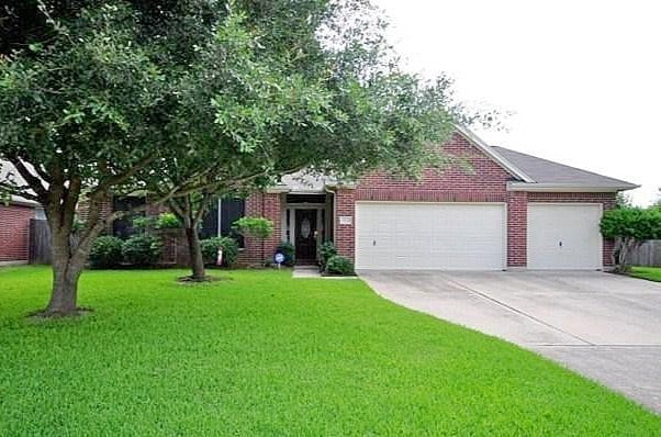 view of front of property featuring a garage, concrete driveway, a front lawn, and brick siding