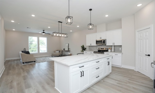 kitchen featuring white cabinetry, hanging light fixtures, a kitchen island, and appliances with stainless steel finishes