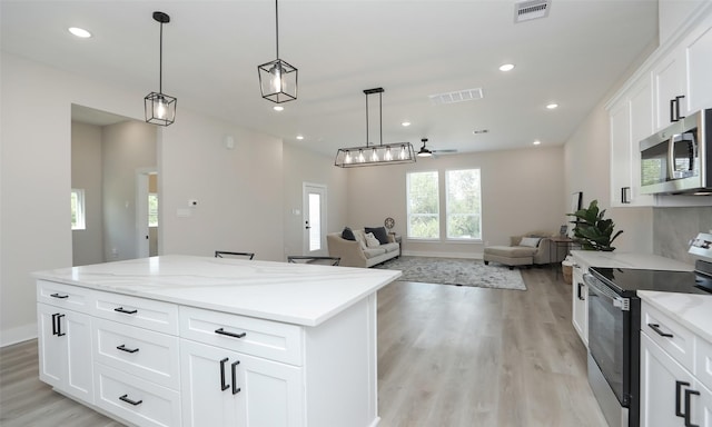 kitchen with hanging light fixtures, stainless steel appliances, white cabinets, and a kitchen island