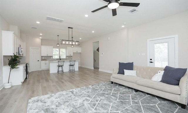 living room with light hardwood / wood-style flooring and ceiling fan