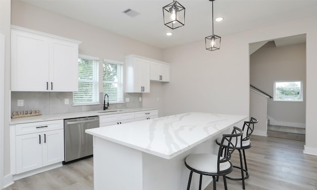 kitchen featuring white cabinetry, dishwasher, sink, and hanging light fixtures