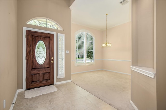 carpeted foyer entrance featuring crown molding and an inviting chandelier