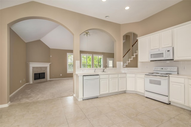 kitchen with lofted ceiling, white appliances, decorative backsplash, and white cabinets