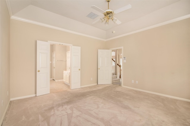 unfurnished bedroom featuring ensuite bath, light colored carpet, ornamental molding, a raised ceiling, and ceiling fan