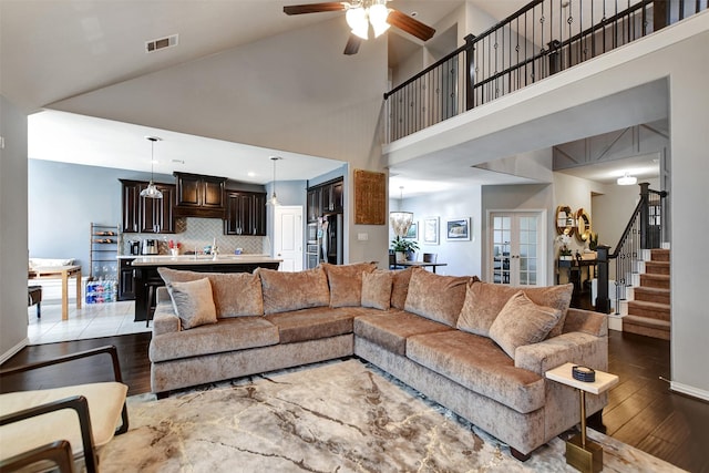 living room featuring a towering ceiling, hardwood / wood-style floors, ceiling fan, and french doors