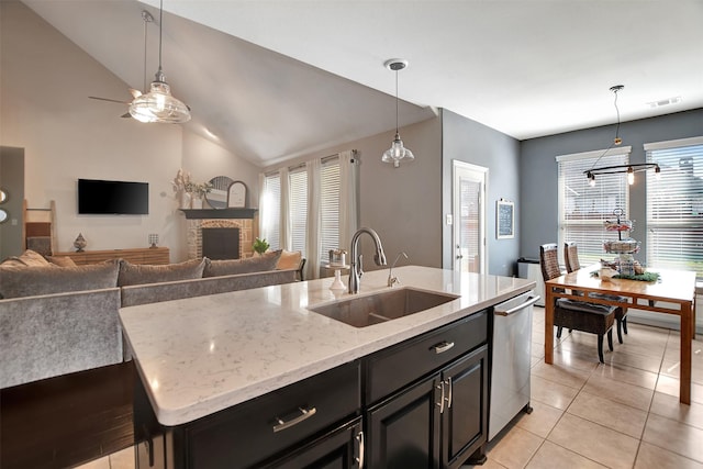 kitchen featuring sink, a kitchen island with sink, light stone countertops, decorative light fixtures, and stainless steel dishwasher