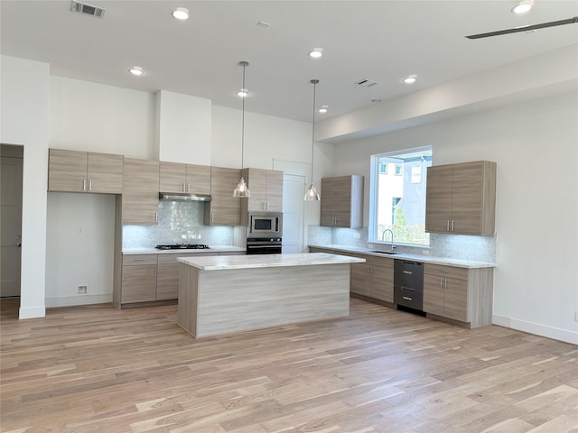 kitchen with sink, a center island, hanging light fixtures, stainless steel microwave, and wall oven