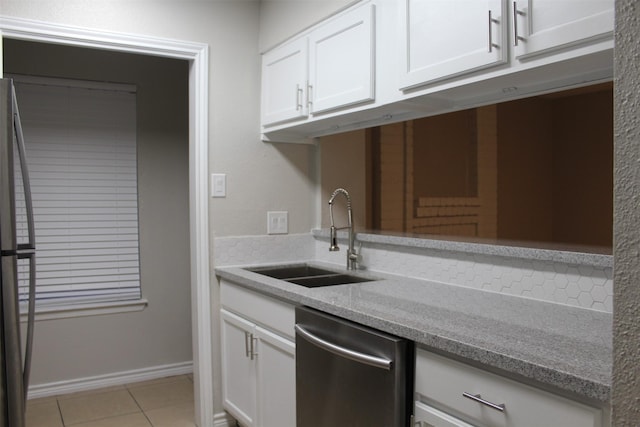 kitchen with sink, light tile patterned floors, appliances with stainless steel finishes, light stone countertops, and white cabinets