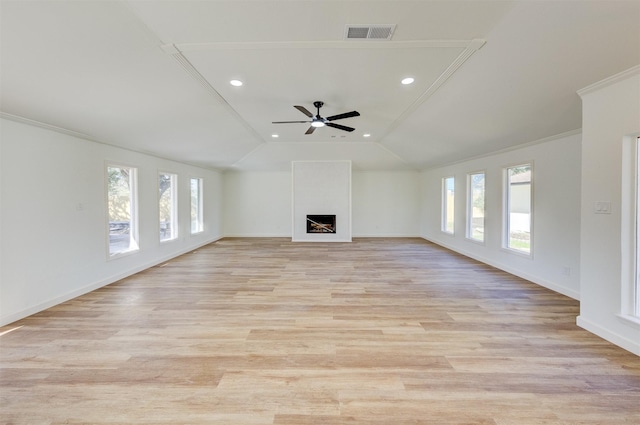 unfurnished living room featuring vaulted ceiling, a healthy amount of sunlight, a fireplace, and light hardwood / wood-style floors