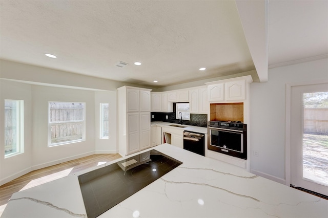 kitchen with sink, dishwasher, white cabinetry, wall oven, and tasteful backsplash