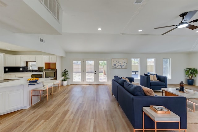 living room featuring ceiling fan, sink, light wood-type flooring, and french doors