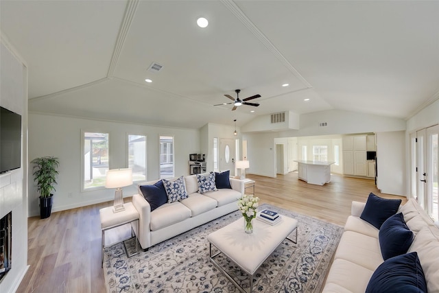 living room featuring a fireplace, vaulted ceiling, light hardwood / wood-style floors, and french doors