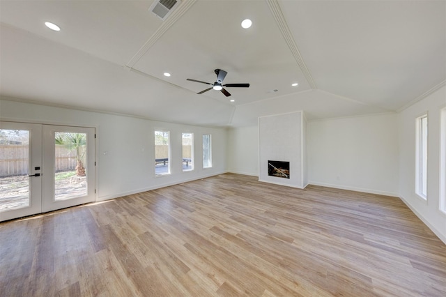 unfurnished living room with lofted ceiling, ornamental molding, ceiling fan, light wood-type flooring, and french doors