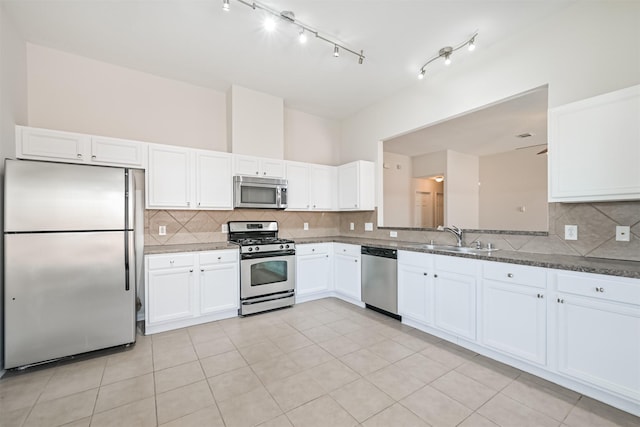 kitchen featuring white cabinetry, stainless steel appliances, sink, and dark stone counters