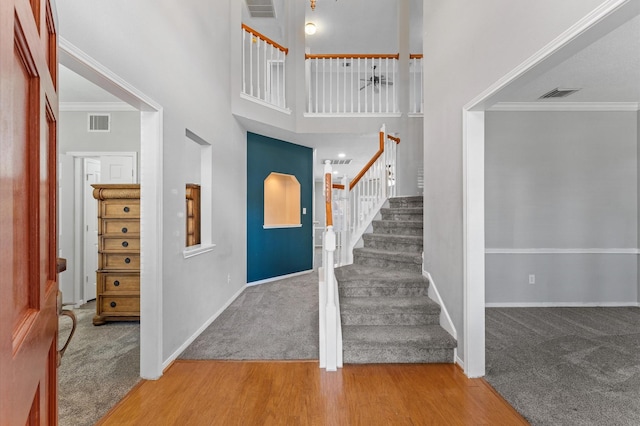 entryway featuring hardwood / wood-style flooring, ornamental molding, and a towering ceiling